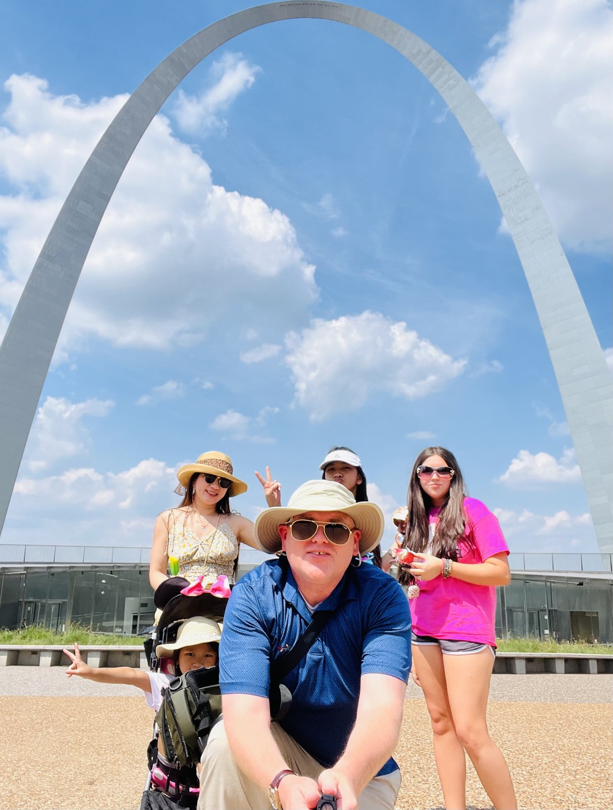 The family crowded under the curve of the Arch on a bright, cloud-flecked day, Davis crouched in front and Diem in a straw hat behind him. Gateway Arch, St. Louis, Missouri, May 31.